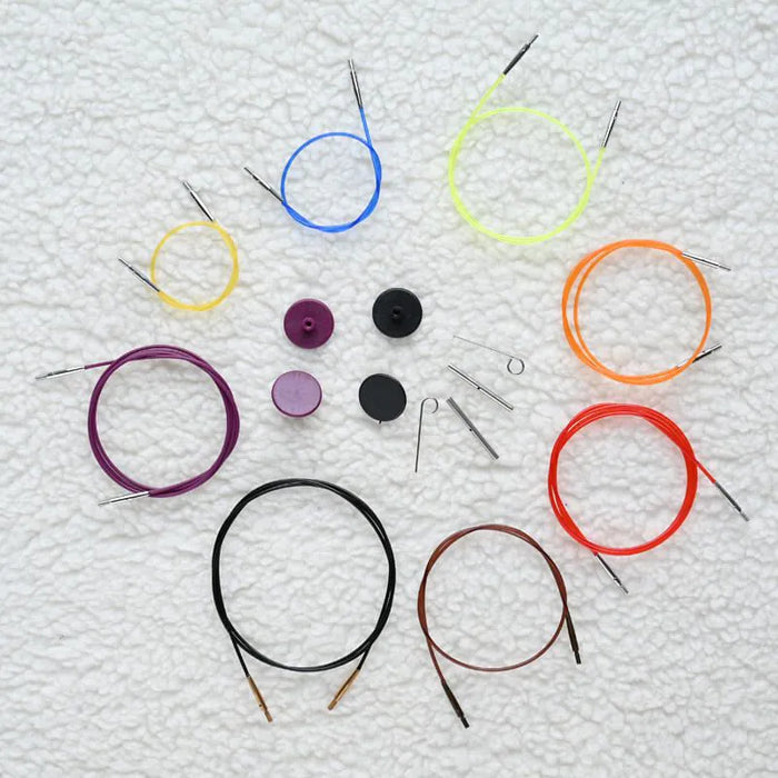 Set of colorful circular knitting needles and accessories on a textured white background