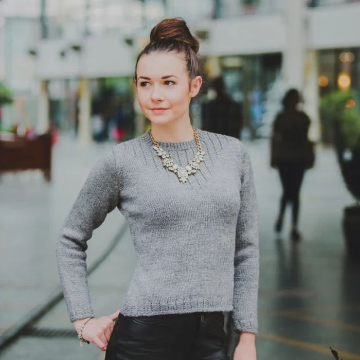 Woman wearing a classic gray knitted sweater, suitable for all sizes from XS to XXL, made from pure wool.