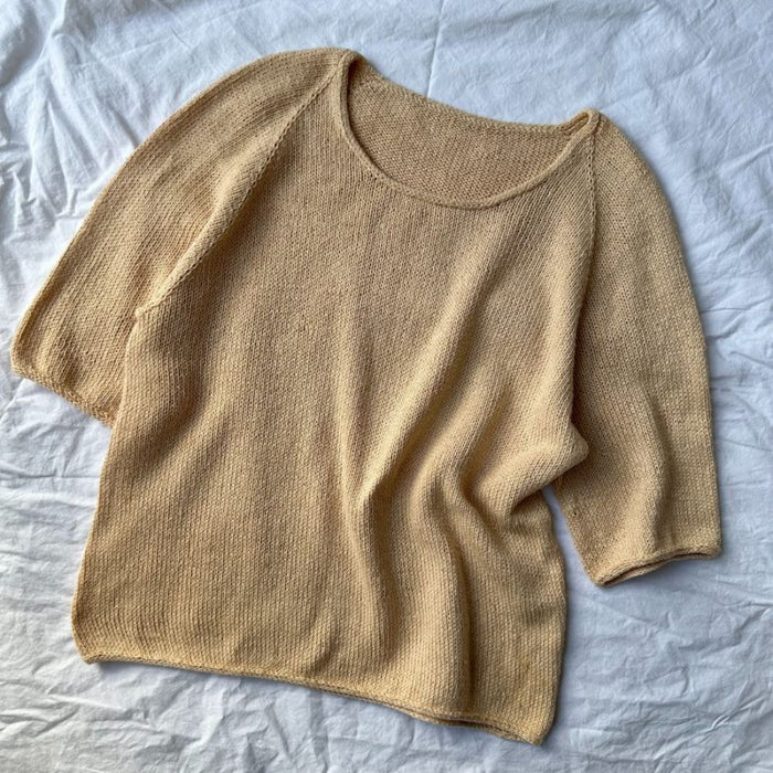 Cumulus Tee O-neck knitting pattern by PetiteKnit laid on fabric background.