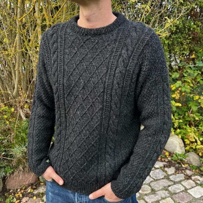 Men's navy cable-knit sweater by PetiteKnit, outdoor setting.