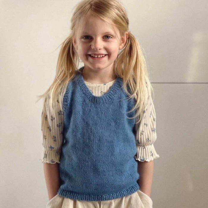 Child wearing blue Stockholm Slipover Mini knitted vest from PetiteKnit.