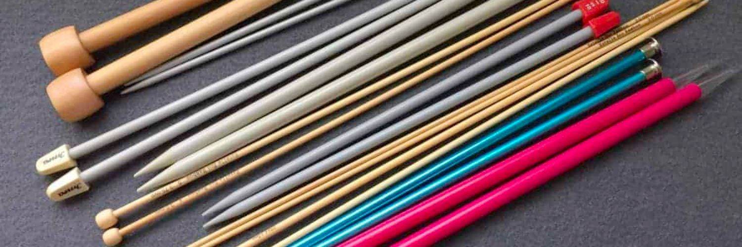 Various different types of knitting needles including bamboo, metal, plastic, wooden, and carbon fiber on a white background