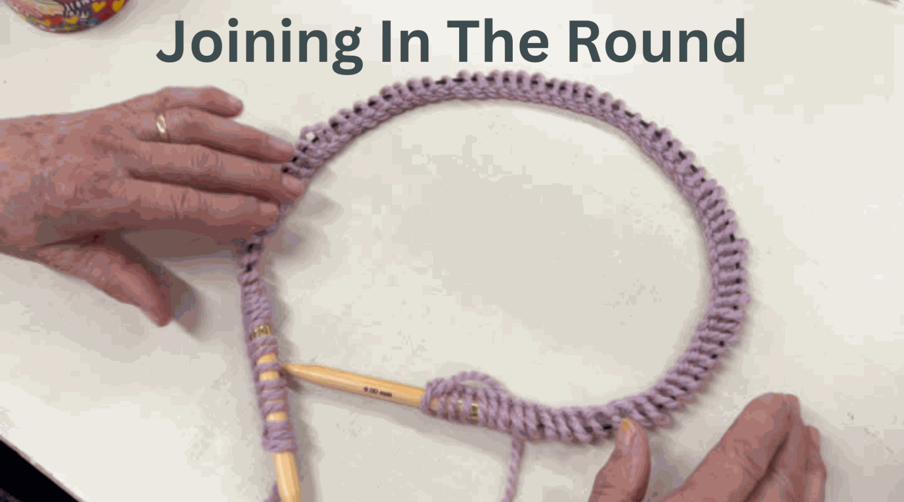 Hands joining knitting stitches in the round on circular needles
