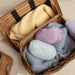 Knitting project bag in taupe leather, holding colorful yarn balls and knitting needles.