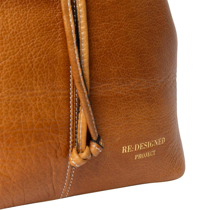 Burned tan genuine leather bucket knitting bag with gold accents and adjustable strap.