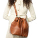 Genuine leather knitting bucket bag in walnut with adjustable strap.
