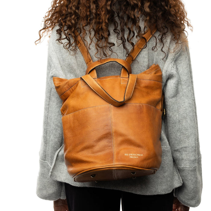Project 24 Backpack in burned tan leather being worn, featuring multiple pockets for organization.
