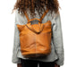 Project 24 Backpack in burned tan leather being worn, featuring multiple pockets for organization.