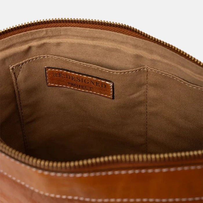 Large handcrafted leather knitting bag in burnt tan and gold with open pockets and zipper closure.