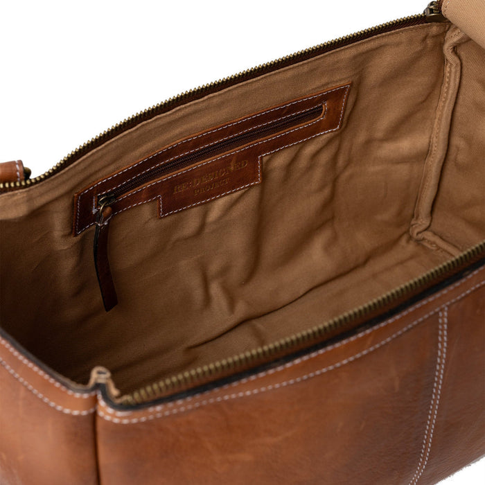 Leather knitting bag with side handle, adjustable strap, and multiple pockets for knitting accessories, in walnut color.