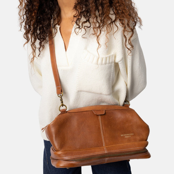 Knitting bag in walnut leather with shoulder strap and multiple compartments.