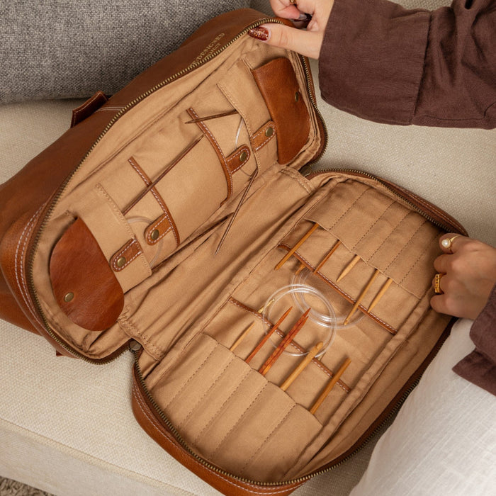 Knitting bag in walnut leather with compartments for needles and notions, and an optional shoulder strap.