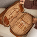 Knitting bag in walnut leather with compartments for needles and notions, and an optional shoulder strap.
