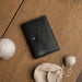 Black and gold leather knitting bag for circular needles on wooden table.