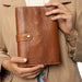 Knitting bag for circular needles in walnut gold leather with pockets and snap closure.