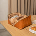 Knitting project bag in burned tan and gold leather with needle pockets on a wooden table.