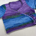 Variegated knit crossover jacket for babies, featuring ribbed detailing and colorful stripes.