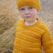 Adorable child wearing Goldie Sweater & Hat knit in mustard yellow merino wool, with striped texture and diamond pattern.