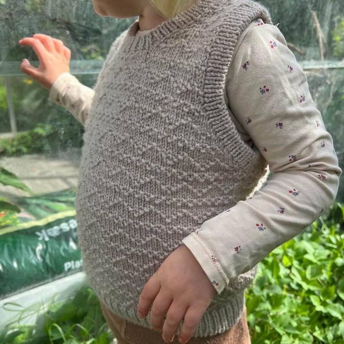 Child wearing beige Sille Slipover Mini knitted vest from PetiteKnit x Sandnes Garn kit in Cardamom color