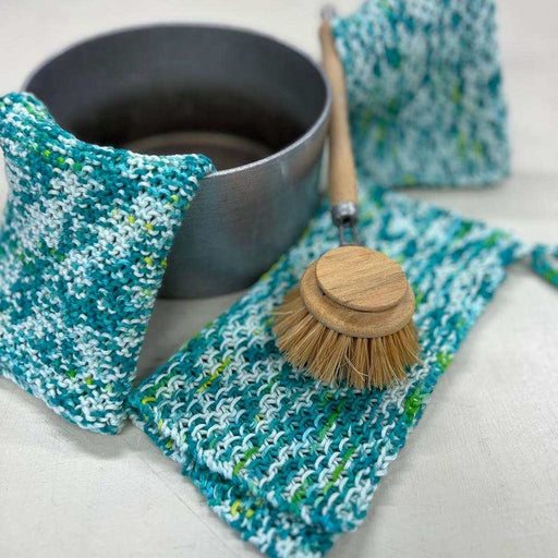 Blue, white and green Waves knitted washcloths beside a bowl and wooden dish brush