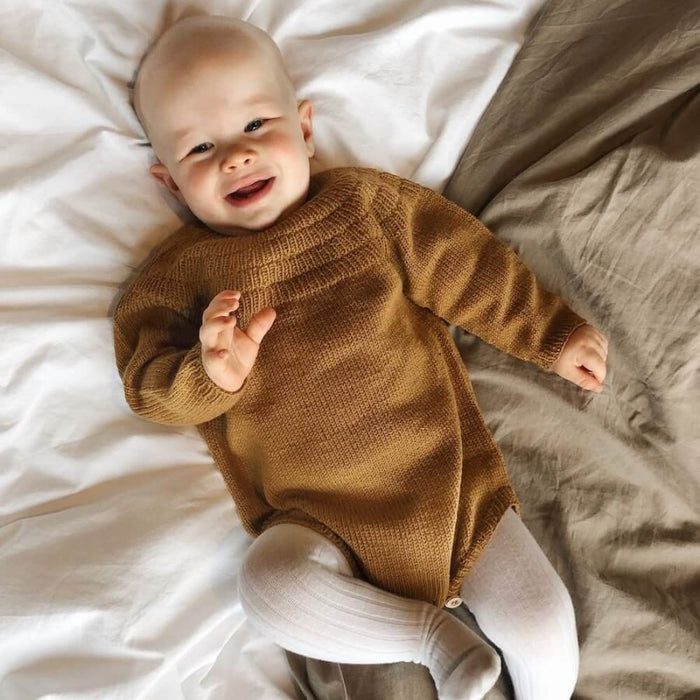 Baby wearing Anker's Suit knitted romper in brown, PetiteKnit pattern for infants 1-24 months.