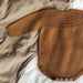 Anker's Suit Knitting Pattern by PetiteKnit showcasing a brown romper with ribbed yoke and button closures, suitable for infants.