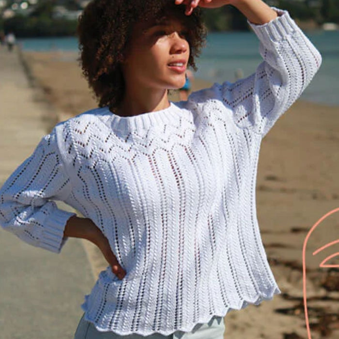 Woman wearing a knitted white cotton lace sweater on the beach.