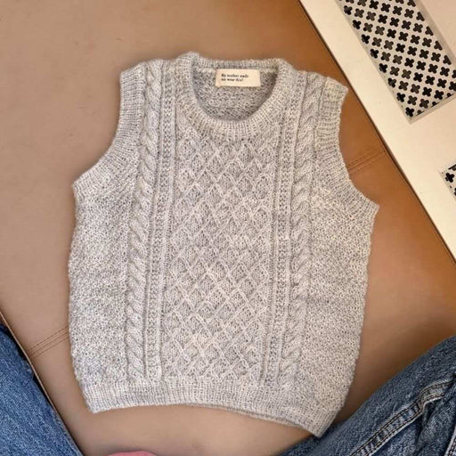 Knitting pattern for Moby Slipover Mini with texture and cable design by PetiteKnit displayed on a brown surface.