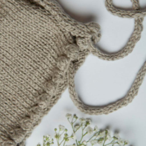 Noe Bobble Bonnet knitting pattern showcasing textured bobbles and ties.