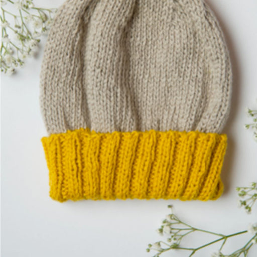 Cozy knitted Sol Hat with yellow ribbed brim and beige body, showcasing a seamless design.