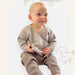 Baby wearing knitted tie cardigan and pants set; knitting pattern for Crucci Luxury Merino Crepe 4ply, sizes 0-12 months.