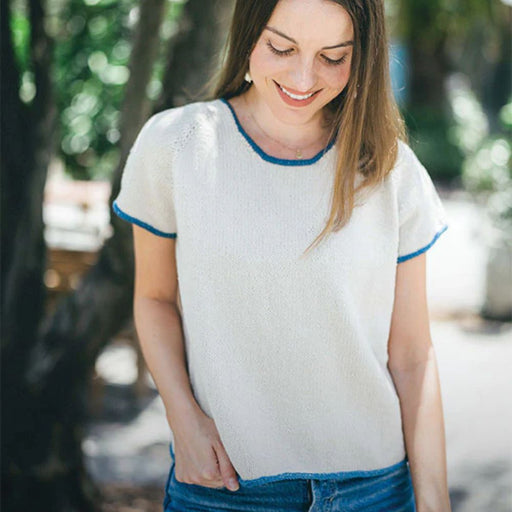 Woman wearing a hand-knit cotton t-shirt from top down pattern with blue trims, using intermediate knitting pattern.