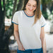 Woman wearing a hand-knit cotton t-shirt from top down pattern with blue trims, using intermediate knitting pattern.