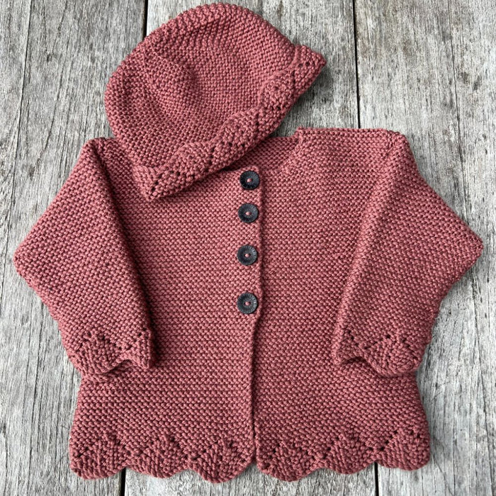 Bobbie Cardigan and Hat Knitting Pattern with lace edge in 8ply yarn on wooden background.