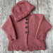 Bobbie Cardigan and Hat Knitting Pattern with lace edge in 8ply yarn on wooden background.