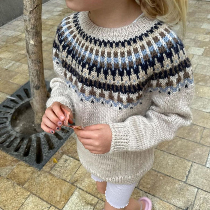 Child wearing Celeste Sweater Junior with circular yoke and colorwork pattern by PetiteKnit.