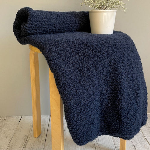 Cosy Alpaca Yarns Cloud blanket on wooden stool, knitting pattern project.