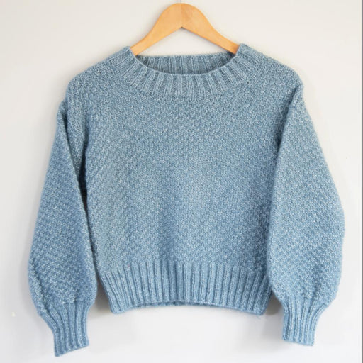 Cropped sweater knitting pattern with textured stitch, long sleeves, and ribbed crew neckline.