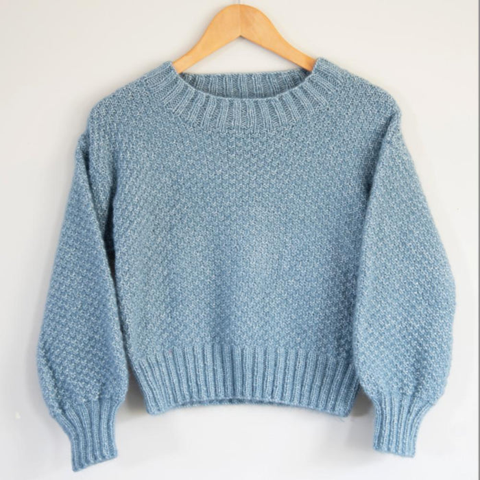 Cropped sweater knitting pattern with textured stitch, long sleeves, and ribbed crew neckline.
