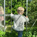 Child wearing a textured white knitted sweater in a garden setting.