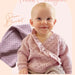 Baby wearing frilled cardigan; pram blanket in background; knitting pattern CRU2317.