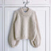 Holiday sweater knitting pattern by PetiteKnit, featuring cozy oversized style with ribbed cuffs and hem in cream color.