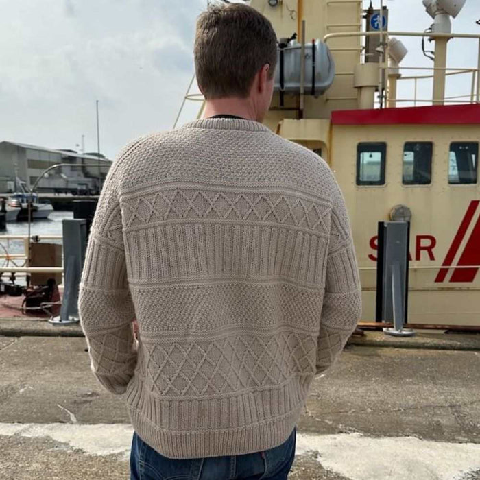 Ingrid Sweater Man knitted with textured patterns outdoors, shown from back.