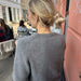 Woman wearing grey Maggie Cardigan from PetiteKnit, side view in outdoor setting.
