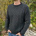 Men's navy cable-knit sweater by PetiteKnit, outdoor setting.