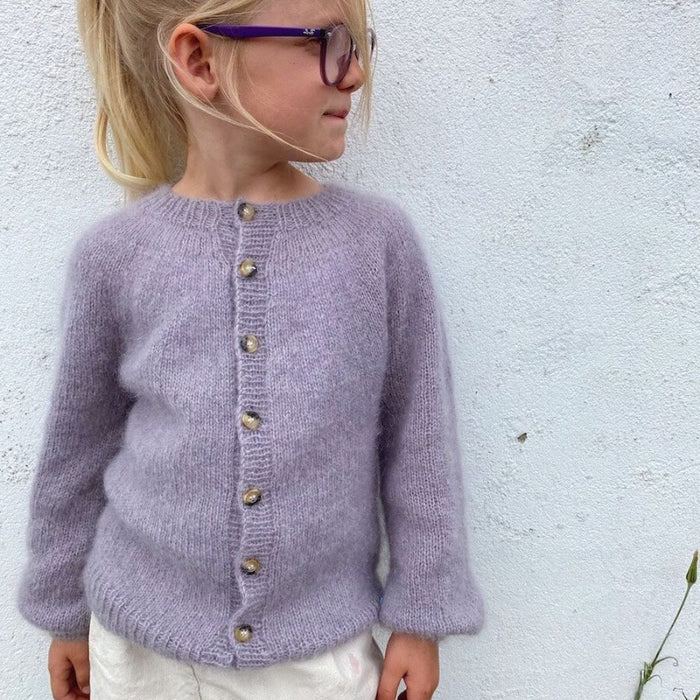 Novice Cardigan Junior Mohair Edition by PetiteKnit, child wearing purple knit cardigan with buttons, side view.