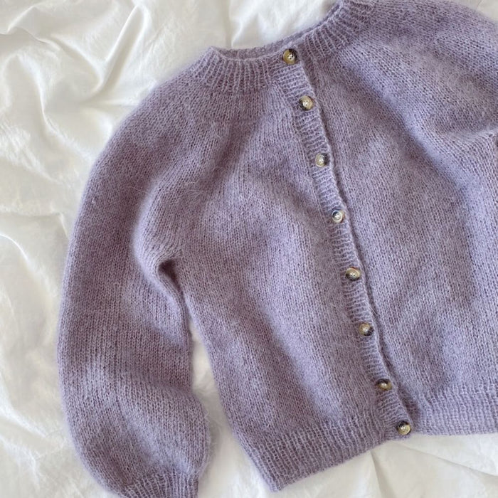 Novice Cardigan Junior Mohair Edition knitting pattern by PetiteKnit, featuring a lilac stockinette cardigan with round yoke and ribbed edges.