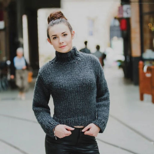 Woman wearing a knitted cowl sweater in a city setting.