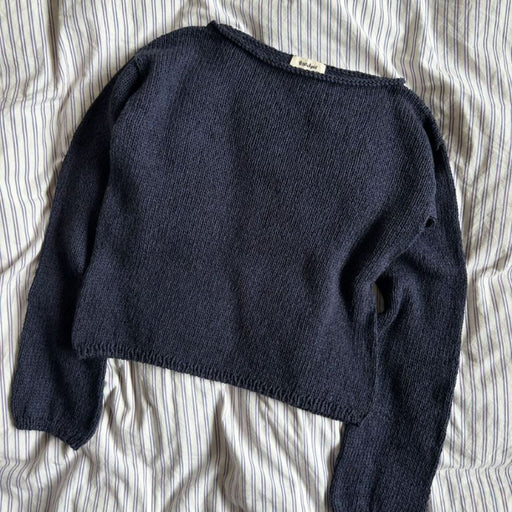 Sevilla Blouse Knitting Pattern by PetiteKnit, featuring a navy blue, boat neck design, knitted in stockinette stitch.