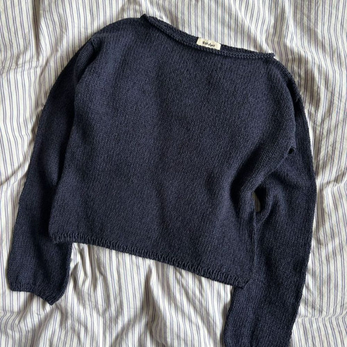 Sevilla Blouse Knitting Pattern by PetiteKnit, featuring a navy blue, boat neck design, knitted in stockinette stitch.